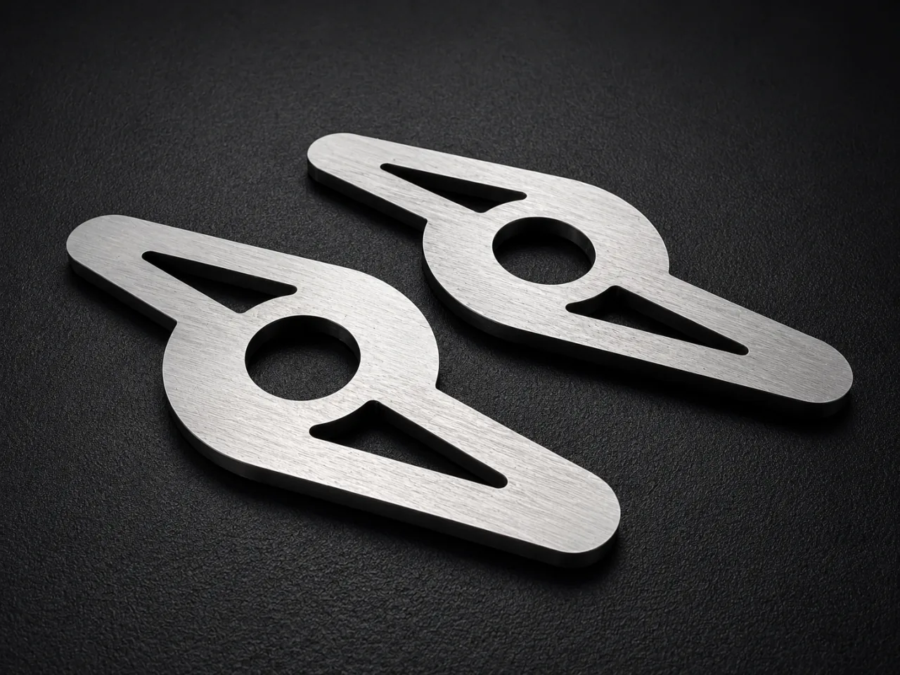 A pair of flat metal profiles with circular centre holes and tapered cut-outs