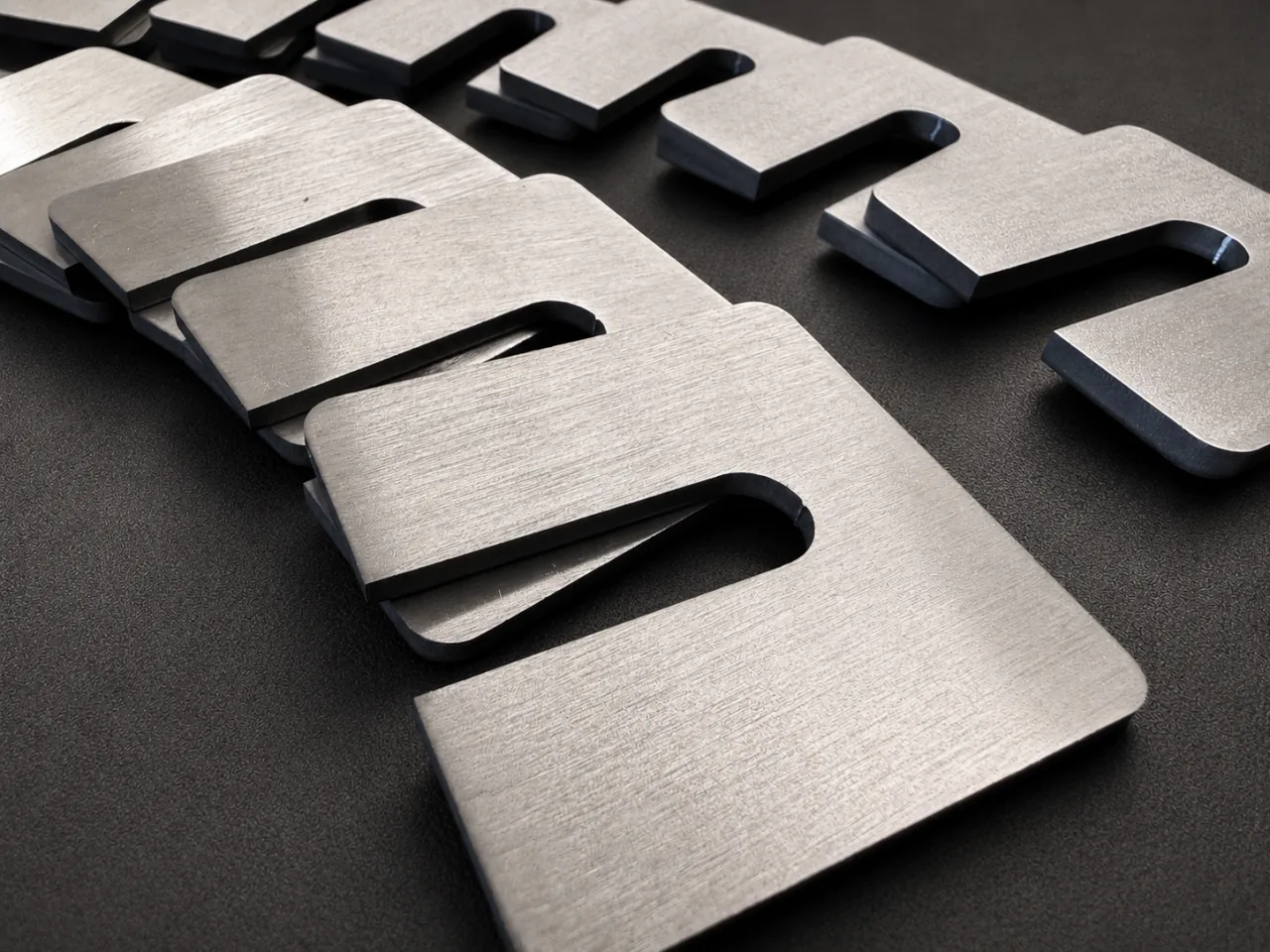 Repeated flat metal parts with wide open-ended slots, arranged in two rows